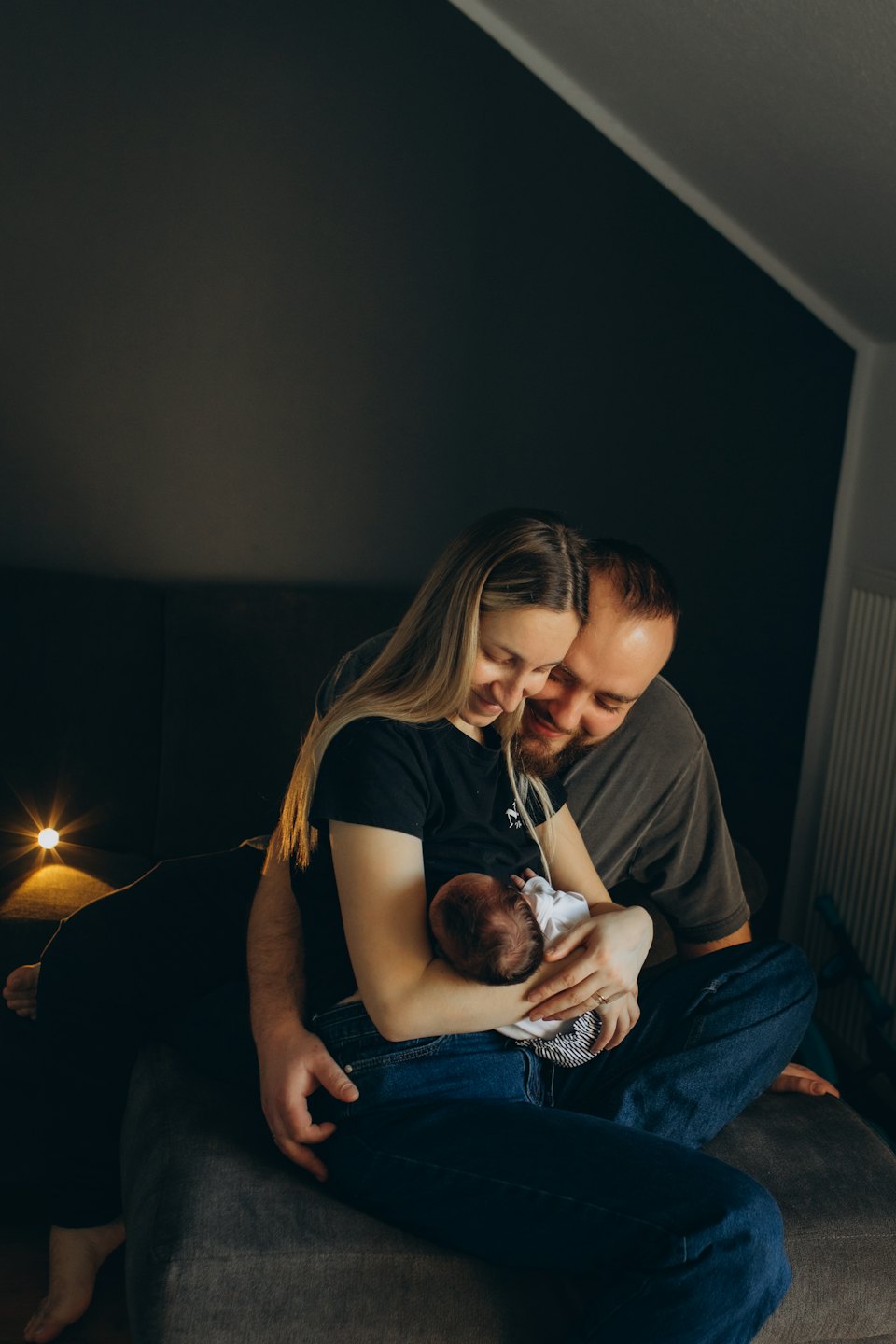 Vanemad kallistavad diivanil istudes oma vastsündinud last.